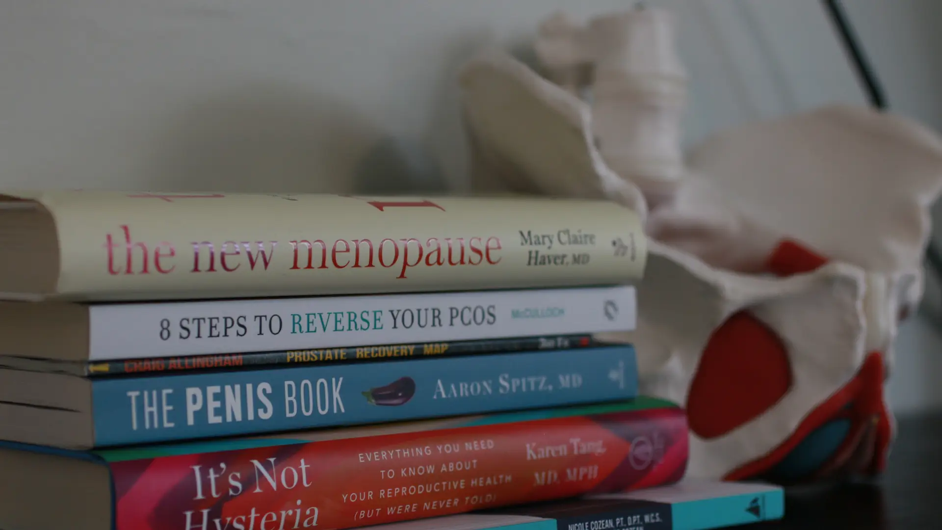 Stacked medical books with pelvic model in background